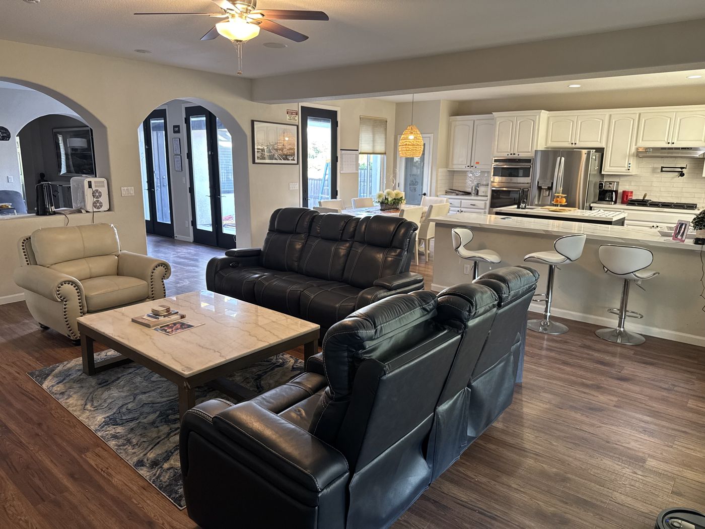 Open-plan living room with leather seating, fireplace, and a view into the kitchen.